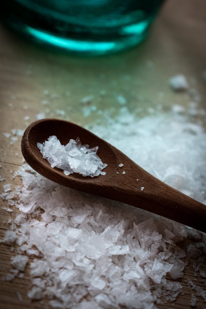 Detailed view of coarse sea salt crystals on a wooden spoon, perfect for culinary themes.